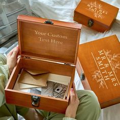 two wooden boxes with personalized items inside on a white sheeted surface, one open and the other closed