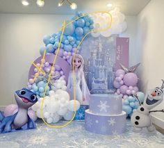 a frozen princess themed birthday party with balloons, cake and figurines on the table