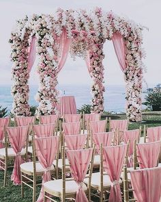 an image of a wedding with pink and white flowers on the arch over the aisle