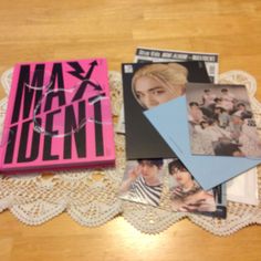 several magazines laying on top of a doily next to a pink book with the cover pulled down