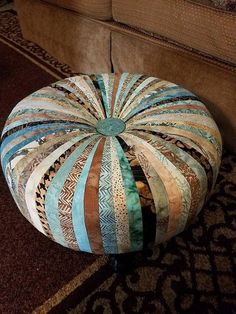 a round patchwork ottoman sitting on top of a rug next to a brown couch