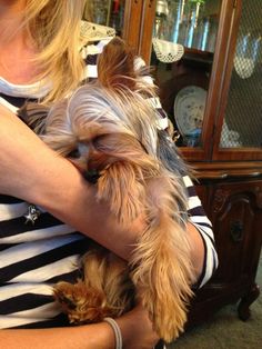 a woman holding a small dog in her arms