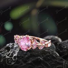 a pink diamond ring sitting on top of a rock