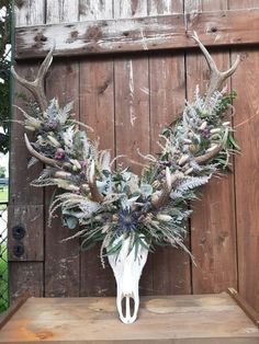 a deer skull with antlers and flowers in front of a wooden wall on display