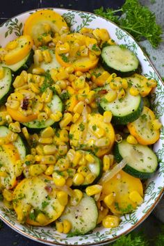 a bowl filled with cucumbers, corn and other vegetables on top of a table