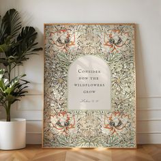 an ornate frame with the words consider how the wildflowers grow on it next to a potted plant