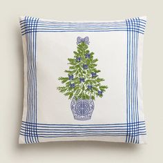 a blue and white pillow with a green christmas tree on the front in a basket