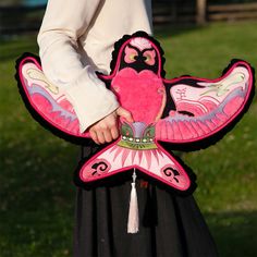 a person holding a pink bird shaped pillow