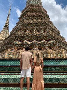 a man and woman standing in front of a tall building with ornate designs on it