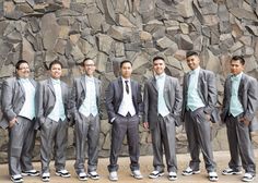 a group of young men standing next to each other in front of a stone wall