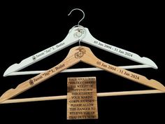 three personalized wooden hangers with names and date engraved on them, hanging from a black background