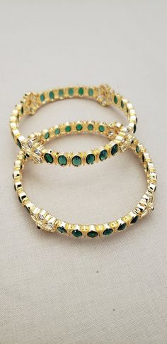 * Handcrafted Gold Plated 2 Bangle Set. * Bangles with pretty Semi Precious Emerald and CZ stones * High Quality 22 K Gold Plated bangles * Sold as a set of 2. Gorgeous gold-plated bangle/ bracelet best exemplifies the careful craftsmanship done on it -- a specialty at Nemali Jewelry. It has special tone of elegance attached to it. The intricate handmade design of the bangle / bracelet set gives it a fresh and original look. Look your best with this elegant-looking bangle / bracelet set from the Green Round Bollywood Jewelry, Green Bollywood Round Jewelry, Elegant Green Bangle For Festive Occasions, Green Bollywood Style Round Jewelry, Green Jeweled Bangle Bracelets, Elegant Green Bangle With Stone Work, Emerald Bollywood Jewelry As Gift, Bollywood Style Emerald Jewelry Gift, Elegant Green Round Bangle