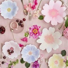 an assortment of flowers on a table with forks and spoons next to each other