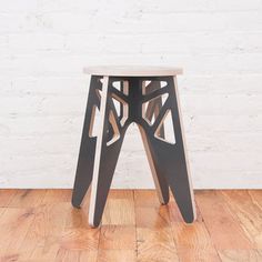 a small stool sitting on top of a wooden floor next to a white brick wall