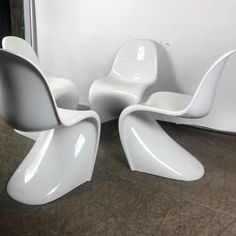 three white chairs sitting next to each other on the floor in front of a mirror