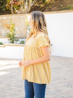 Introducing the Michelle Babydoll Top - Yellow, the perfect addition to your wardrobe! This top is designed with layers of the softest fabric and features patterns that will make you swoon. The flowy and fun design of this top ensures that you'll create a charming look in no time. Crafted with a babydoll fit, the Michelle top is designed to flatter your figure without overwhelming your overall look. Available in sizes Small (0-4), Medium (6-8), Large (10-12), and XL (12-14), you're sure to find Breezy Flowy Spring Top, Breezy Flowy Top For Spring, Casual Flowy Printed Top, Flowy Short Sleeve Breezy Top, Flowy Short Sleeve Tops For Spring, Flowy Tiered Ruffled Tops, Cute Flowy Ruffled Tops, Cute Flowy Tops For Spring, Breezy Flowy Short Sleeve Blouse