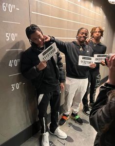 young men standing in front of a wall with numbers on it and one man holding up a sign