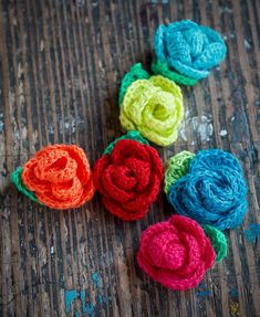 crocheted flowers are arranged on a wooden surface