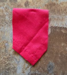 a pink necktie laying on top of a stone wall next to a piece of paper