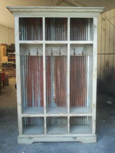 an old white bookcase with glass doors in a storage room filled with junk and other items