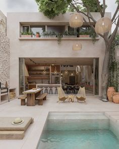 an indoor swimming pool with lounge chairs and tables next to it in front of a house