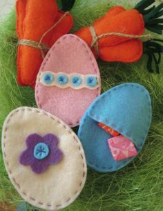 three felt easter eggs on grass with carrots in the background