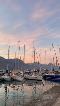 many sailboats are docked in the water at sunset