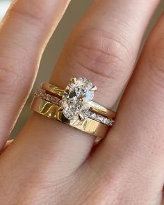 a woman's hand with two gold rings and a diamond ring on her finger