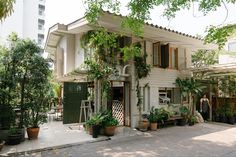 a white house with lots of potted plants on the front and side of it