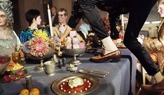 a group of people standing around a table with food and candles on top of it