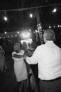 black and white photograph of people dancing at an event with lights in the sky behind them