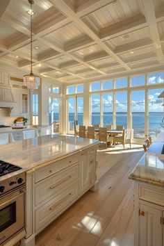 a kitchen with an island, stove and dining room table in front of the ocean