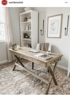 a wooden table sitting on top of a rug in front of a white book shelf