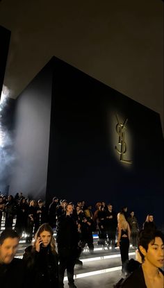 people standing in front of a building at night with fireworks coming from the sky behind them