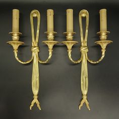 a set of four brass wall lights with candles on each one side and the other end