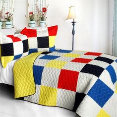 a bed covered in a colorful quilt next to two lamps