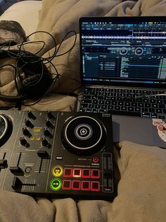 a laptop computer sitting on top of a bed next to a dj's controller