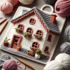 a crocheted house with potted plants and yarn