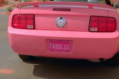 the back end of a pink car with a license plate on it's bumper