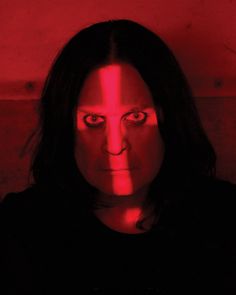 a woman with dark hair and red light shining on her face