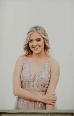 a woman in a dress posing for a photo with her arms crossed and smiling at the camera