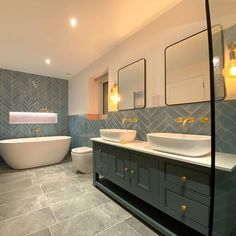 a large bathroom with two sinks and a bathtub in the center, along with an oval mirror on the wall