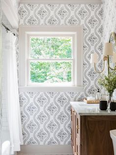 a bathroom with a sink, mirror and wall paper in it's corner area