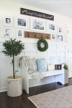 a white bench sitting in the middle of a living room next to a wall with pictures on it