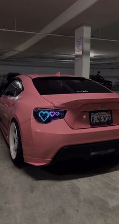 a pink car parked in a parking garage with heart shaped lights on it's trunk