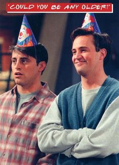 two men standing next to each other wearing party hats