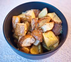 a blue bowl filled with potatoes on top of a white tablecloth covered countertop