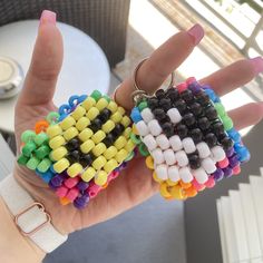 two pieces of colorful beads are held in the palm of a woman's hand