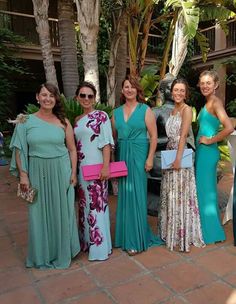 several women in long dresses standing next to each other on a brick floored walkway