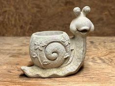 a ceramic snail planter sitting on top of a wooden table